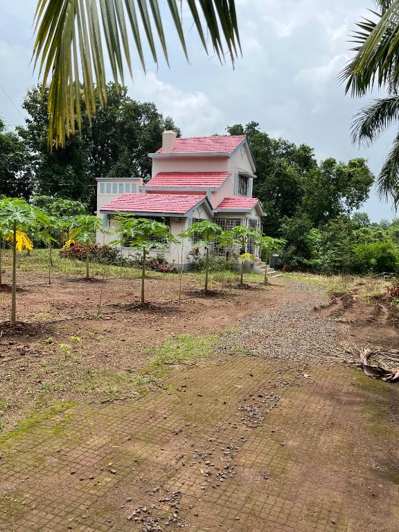 a pink house with a red roof on a field at Aakash Bungalow-EcoFriendlyTourism in Agashi