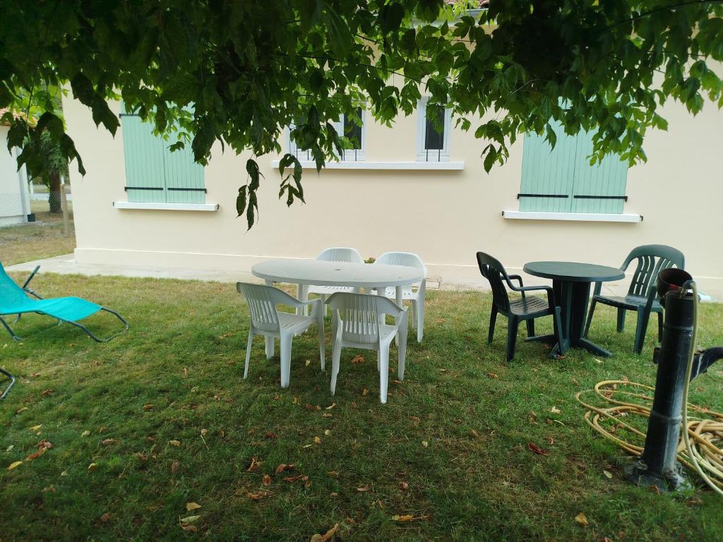 a group of tables and chairs under a tree at Maison de vacances à Lesperon in Lesperon