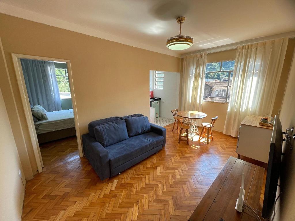 a living room with a blue couch and a table at Conforto praticidade Centro Histórico Petrópolis in Petrópolis
