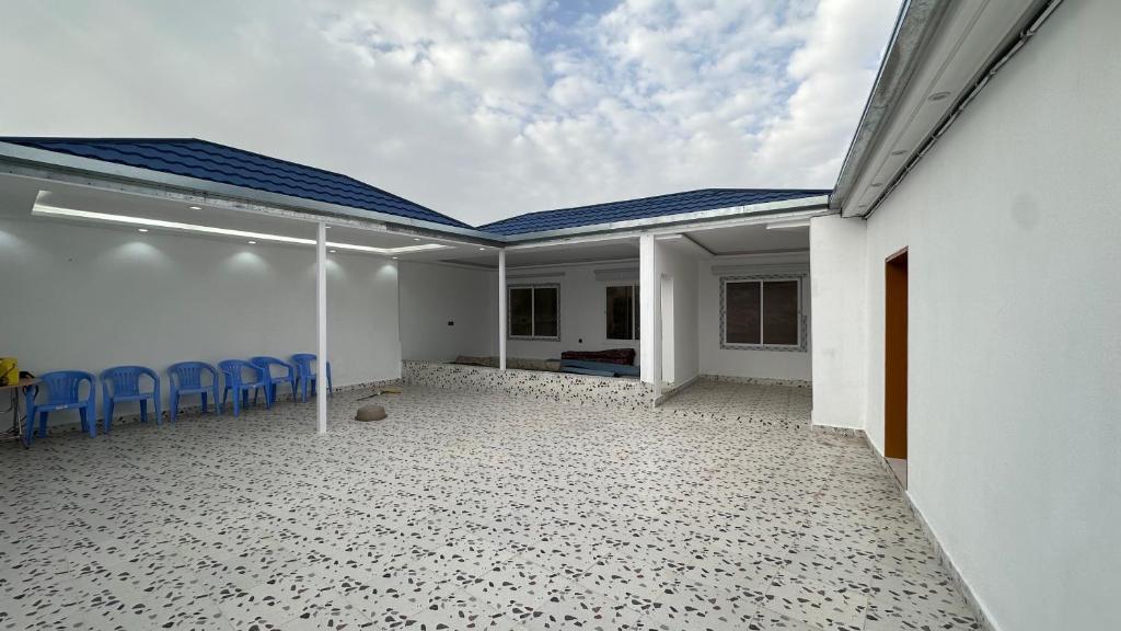 a white house with a patio with blue chairs at استراحة بالهدا in Al Hada
