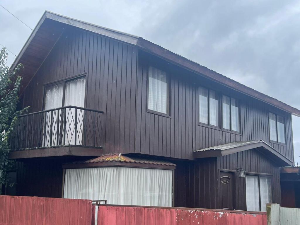 una casa negra con una valla roja delante de ella en Casa Rukalma Centro, en Villarrica
