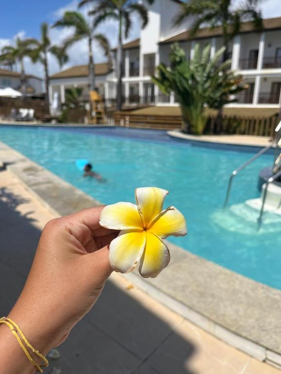 a person holding a flower in front of a swimming pool at Apartamento em Subaúma no Resort Tree Bies in Entre Rios