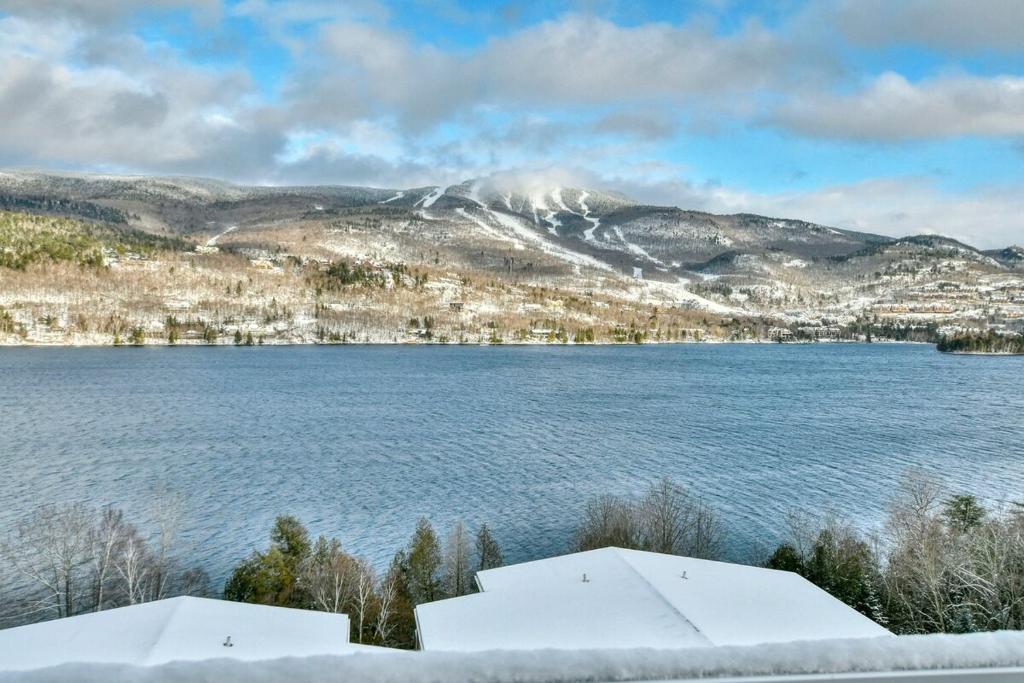 a view of a lake with snow covered mountains at Tremblant mountain view PH71 in Mont-Tremblant