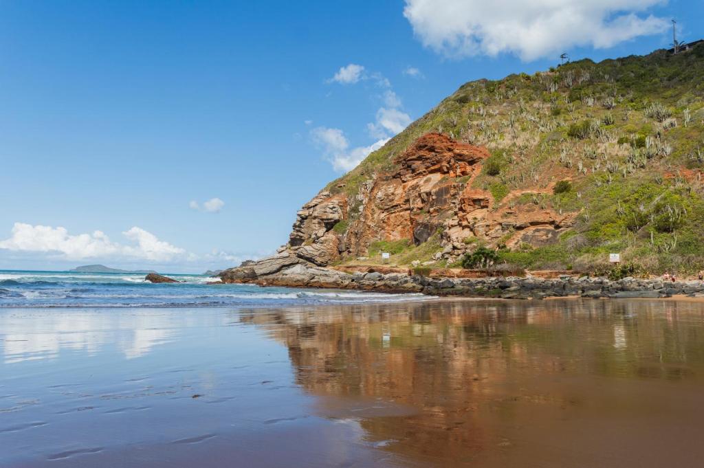 a beach with a cliff and the ocean at Apartamento Jardim Geribá in Búzios
