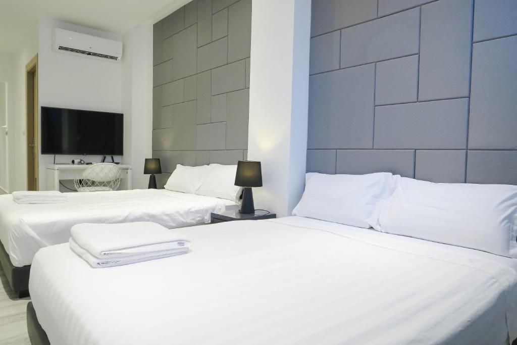 two white beds in a room with a tv at Comfy Studio 3 by Ong Realty in Singapore