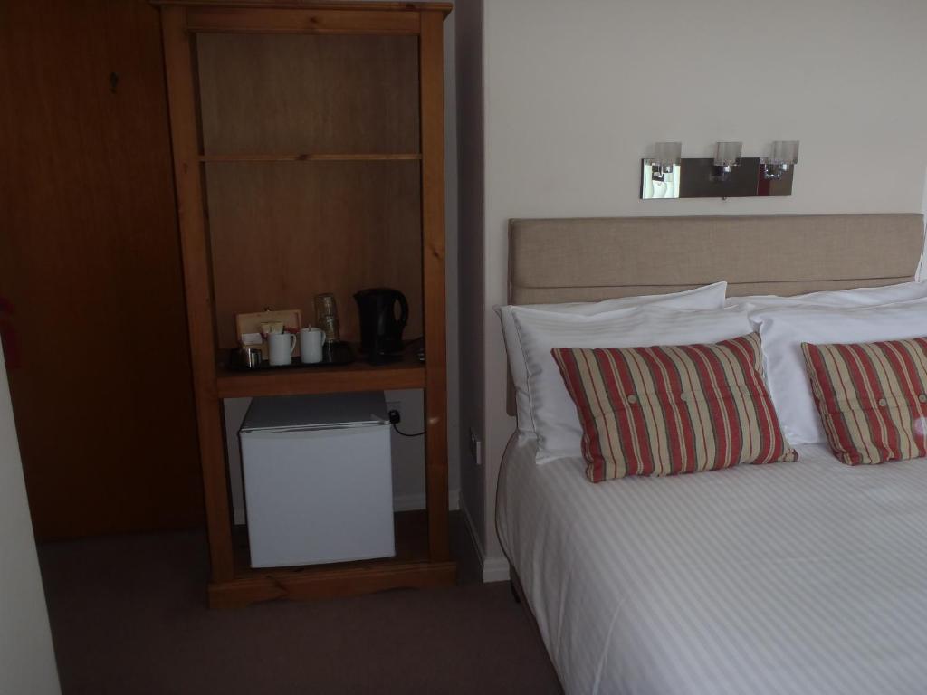 a bed with two pillows and a shelf next to it at Clinmore House in Paignton