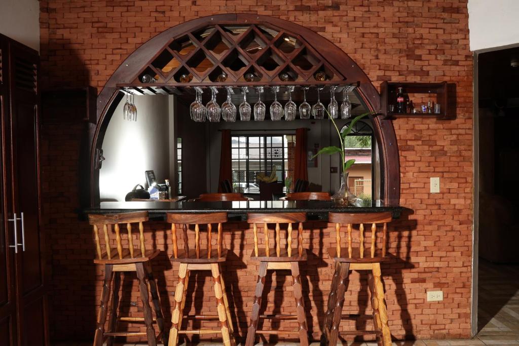 a bar with wooden stools and a brick wall at Novus Stay Boquete in Los Naranjos