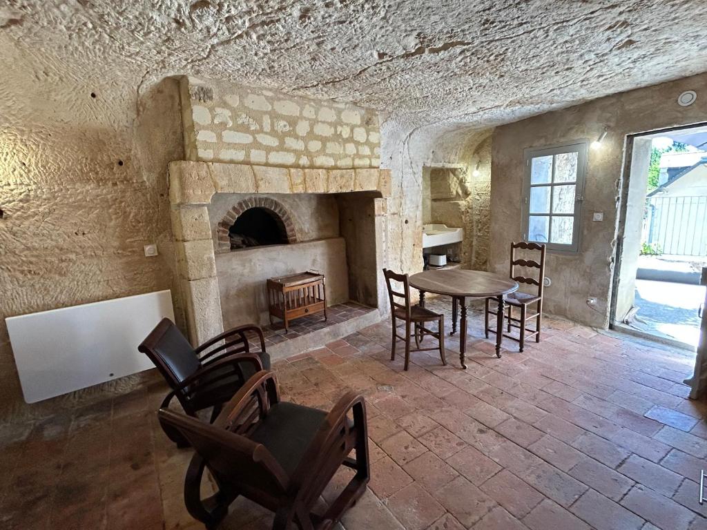 a living room with a table and a fireplace at Habitat troglodyte typique et confortable in Villaines-les-Rochers