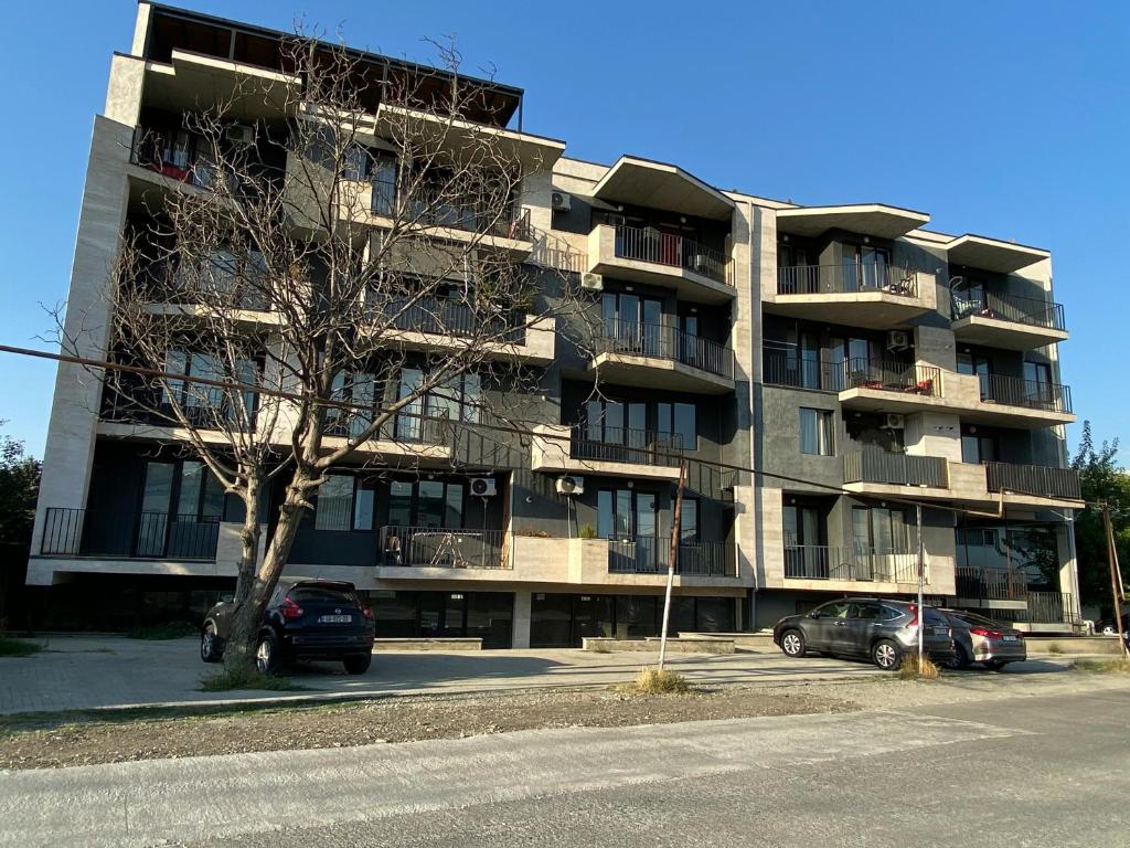 Cozy Apartment For Daily Rent في تبليسي: مبنى سكني فيه سيارات تقف في موقف