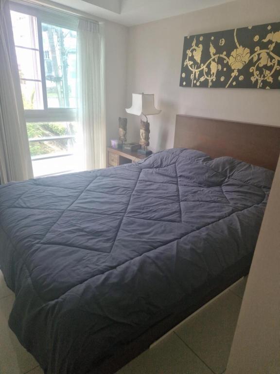 a bedroom with a blue bed with a window at Christian Apartament in Kata Beach