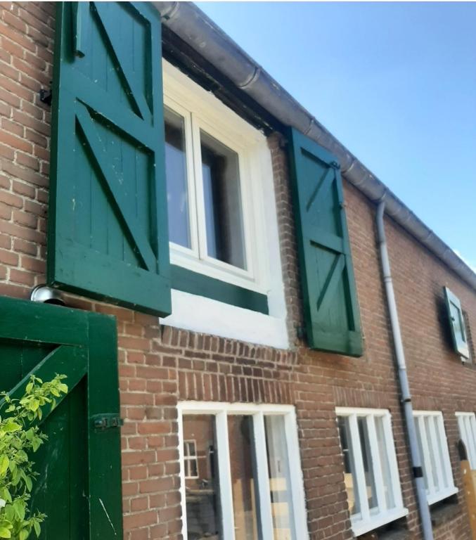 an open window on a brick building with green shutters at BonAparte in Hank