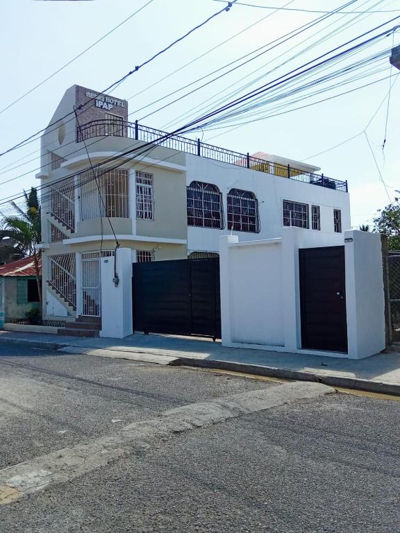a white house with black gates on a street at Apartamentos ipap luperon in Puerto de Luperon
