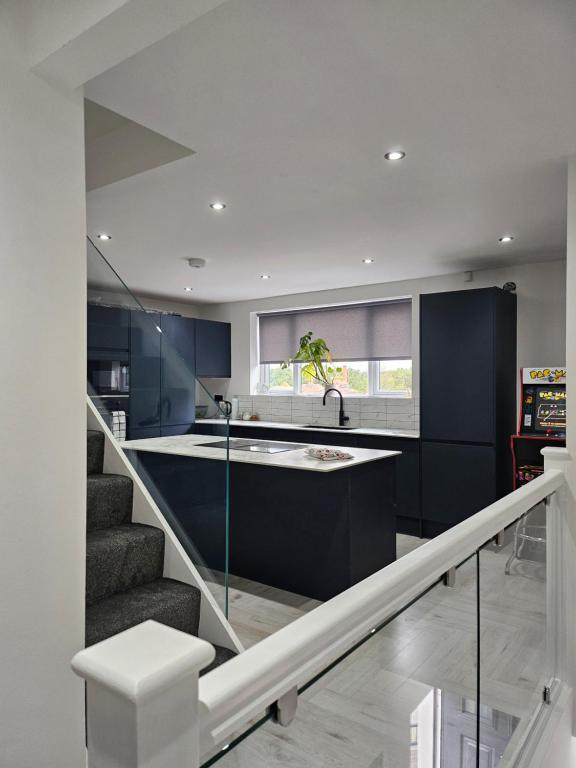 eine Küche mit blauen Schränken und eine Treppe mit einem Waschbecken in der Unterkunft Luxury 3 bed next to city centre in Killingbeck