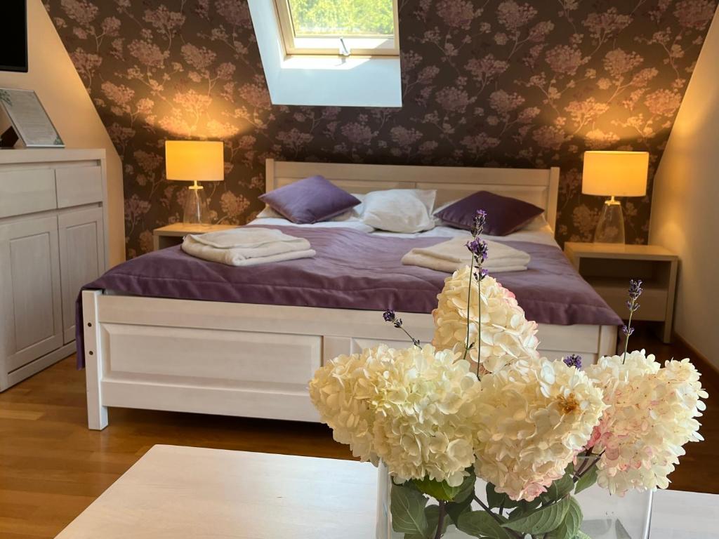 a bedroom with a bed with purple sheets and a vase of flowers at Apartamety i Pokoje Gościnne Na Jaskółczej in Świeradów-Zdrój