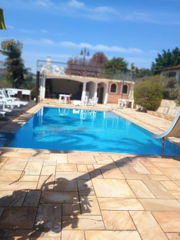 a blue swimming pool with a chair on a patio at Casa de temporada 2 in Serra Negra
