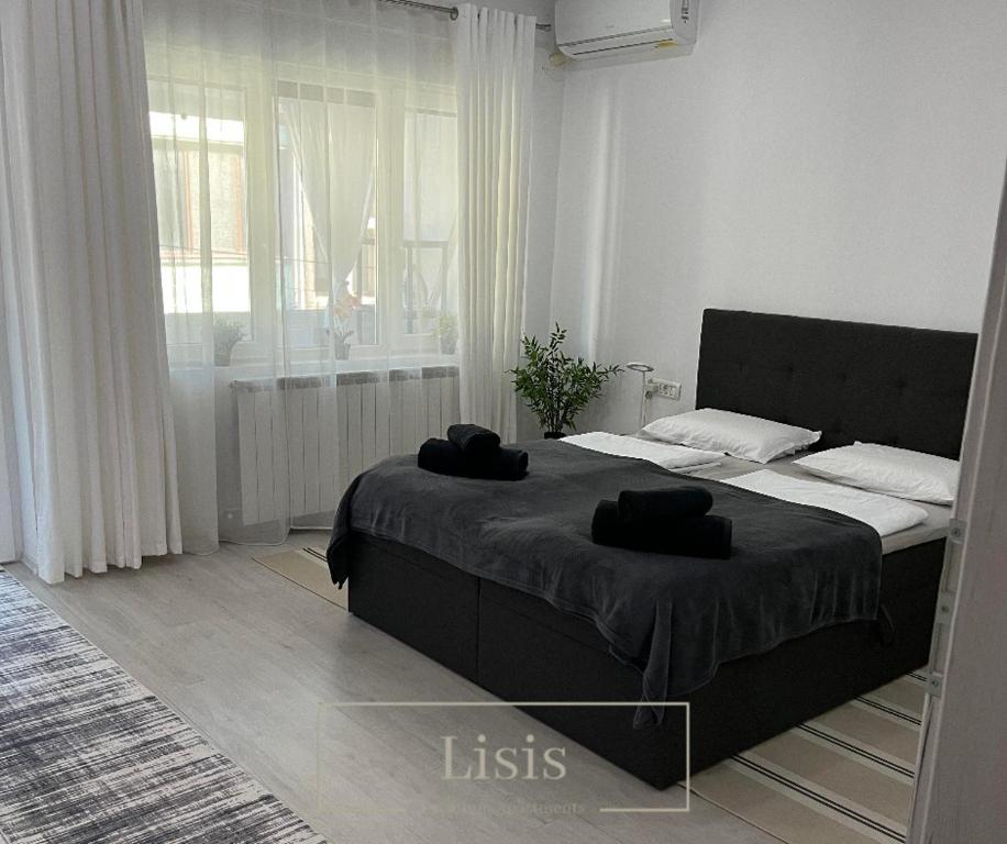a bedroom with a bed with two black towels on it at Lisis Premium Apartments in Reşiţa