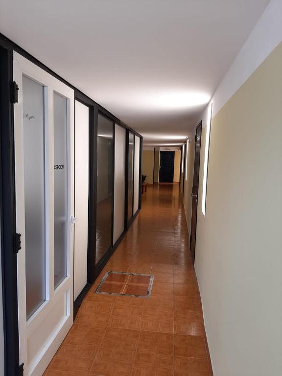 a hallway with a long corridor with glass doors and a tile floor at hena apart 3 in Esquel