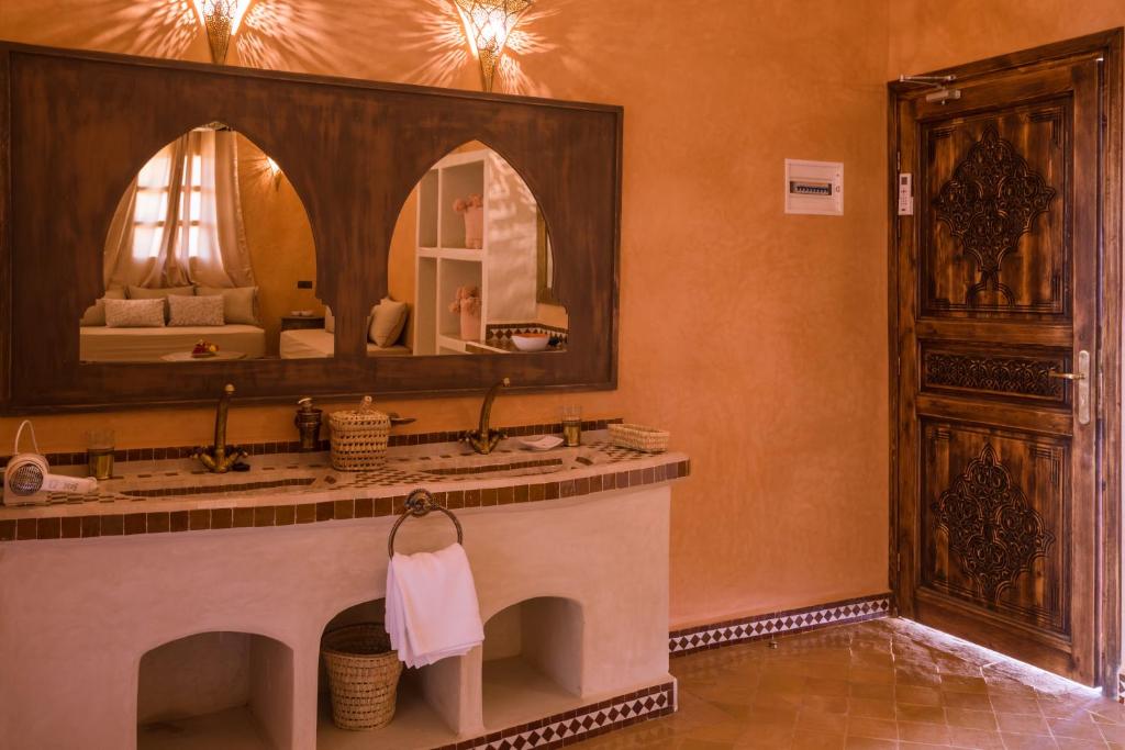 La salle de bains est pourvue d'un grand miroir et d'un lavabo. dans l'établissement Riad Serai Merzouga, à Merzouga