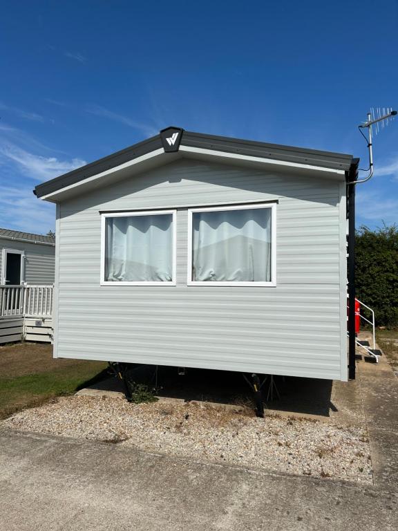 a small white house with a window in a driveway at Blosseys Beach House in South Hayling