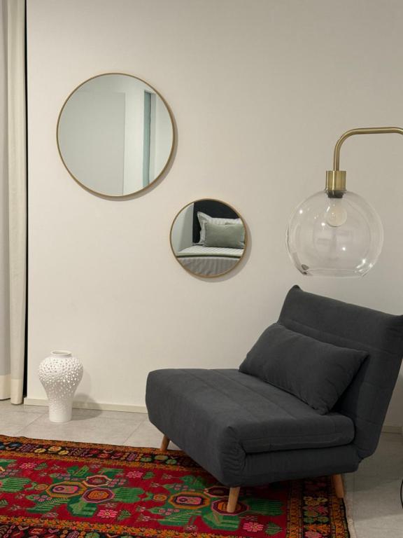 Una sala de estar con una silla y un espejo. en Appartamento VINESSA - Residence OLIVEA, en Riva del Garda