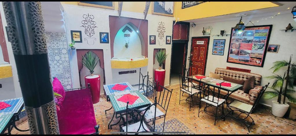 a room with tables and chairs and a room with paintings on the wall at Riad Layla Rouge in Marrakesh