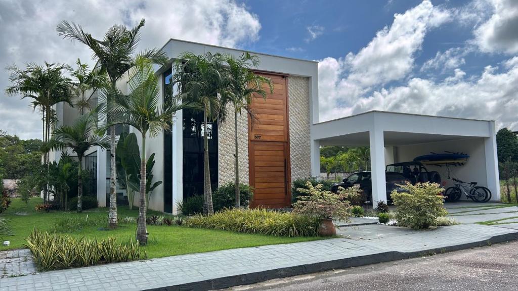 a house with palm trees in front of it at COP 30 BELEM - Casa de Luxo - 4 suítes in Marituba