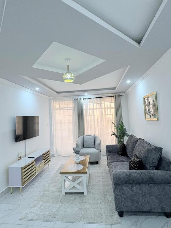 a living room with a couch and a tv at Kevara by H&D Stays in Nanyuki