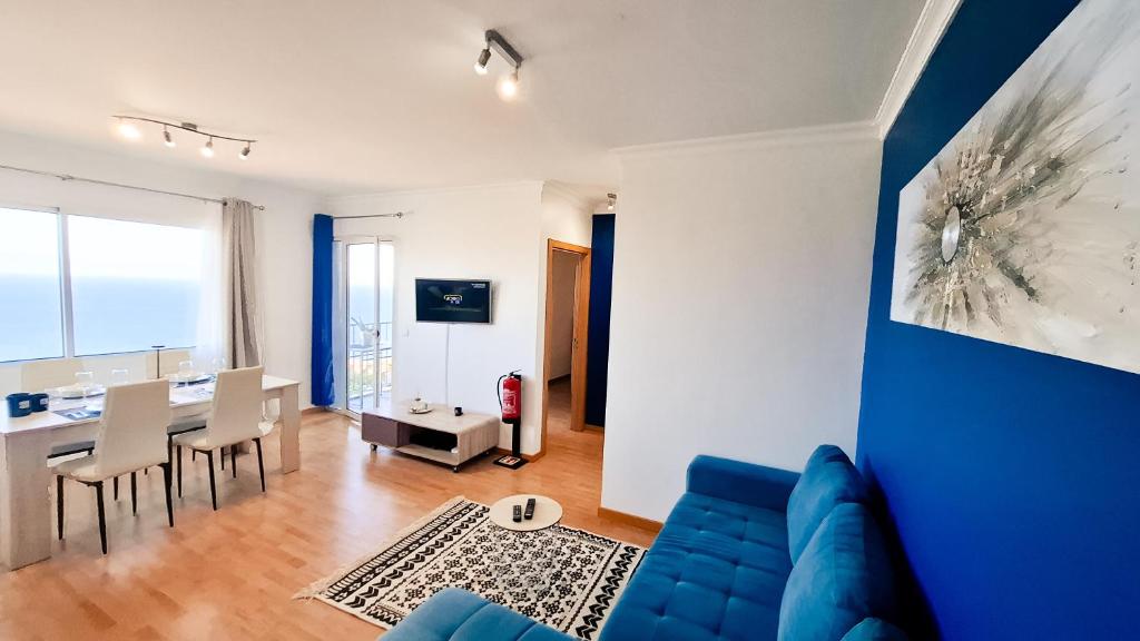 a living room with a blue couch and a dining room at Mãe de Deus - Caniço - Madeira in Caniço