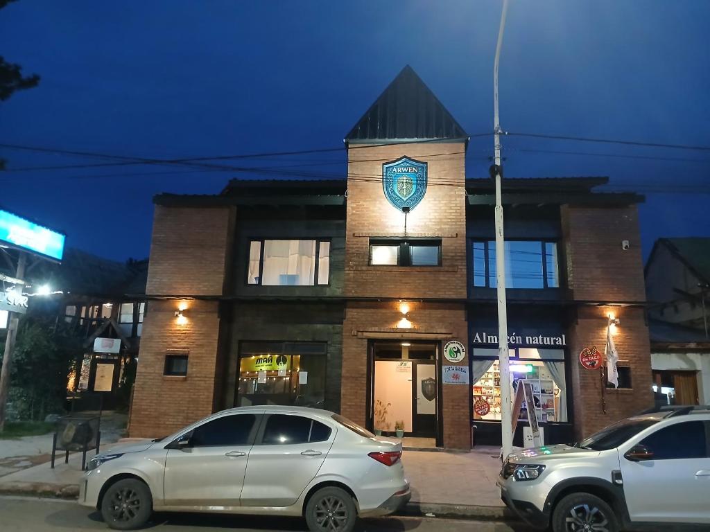 dos coches estacionados frente a un edificio de ladrillo en ARWEN Suites 2, en Trevelín