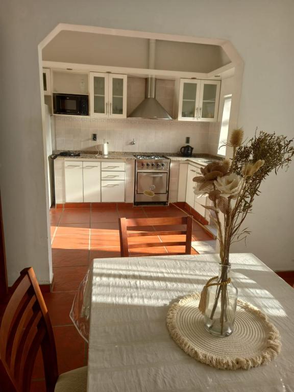 a kitchen with a table with a vase of flowers on it at Alquiler Temporario Casa Cervantes in Paraná