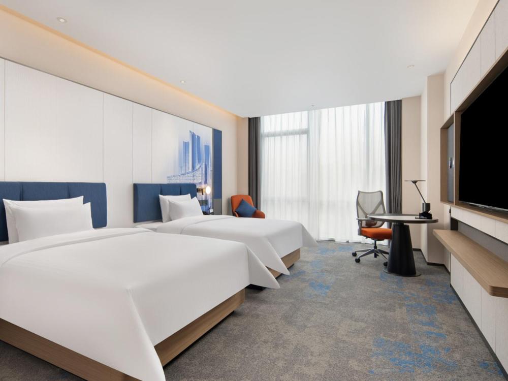 a hotel room with two beds and a flat screen tv at Hampton by Hilton Hefei Xinqiao International Airport in Hefei