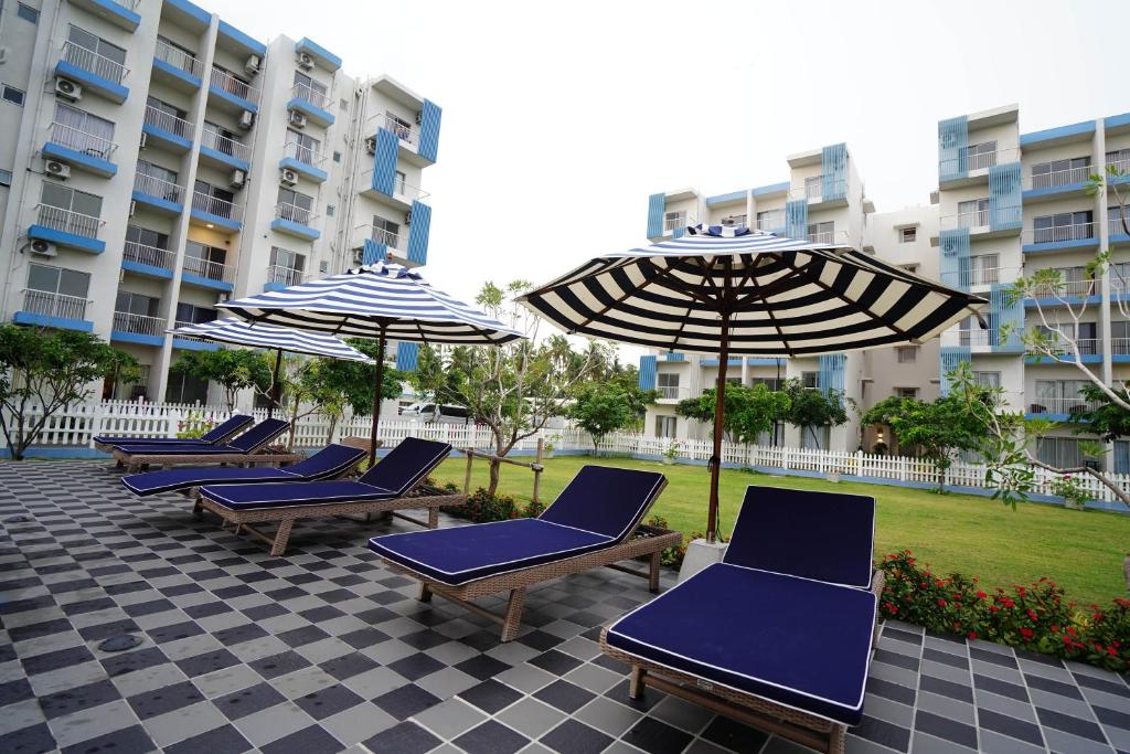 a row of blue chairs and umbrellas on a patio at Lavender Villa Negombo Stylish Airport Retreat in Negombo