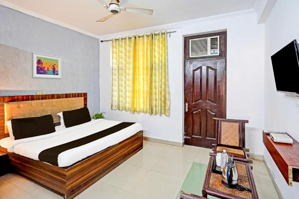 - une chambre avec un lit, une télévision et une porte dans l'établissement Hotel O 9 Palm, à Rājpur