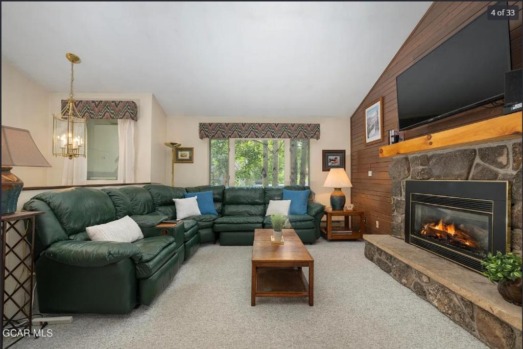 a living room with a green couch and a fireplace at Quaint townhome in downtown Winter Park, Ski and Bikers Paradise, Walk to Town in Winter Park