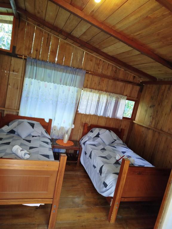 due letti in una stanza con pareti in legno di Larita's MINDO Hospedaje y Casita de campo Los Guayabales a San Carlos
