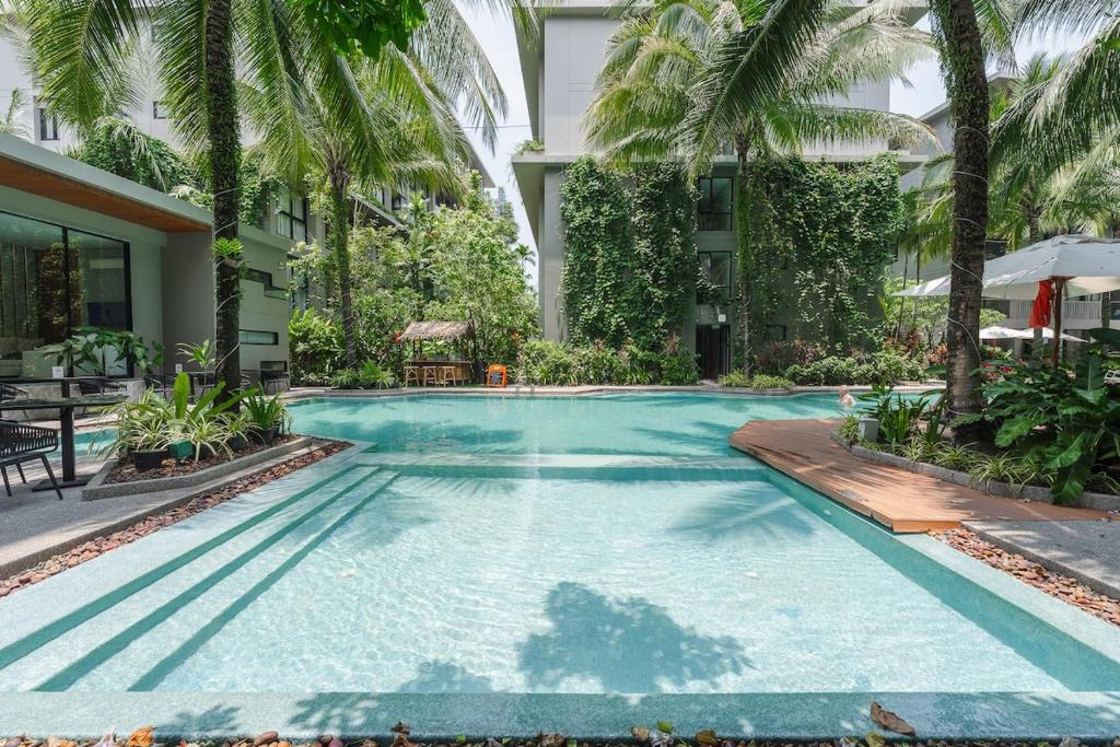 a swimming pool with palm trees and a building at Diamond Resort Phuket walk to Bangtao Beach in Phuket