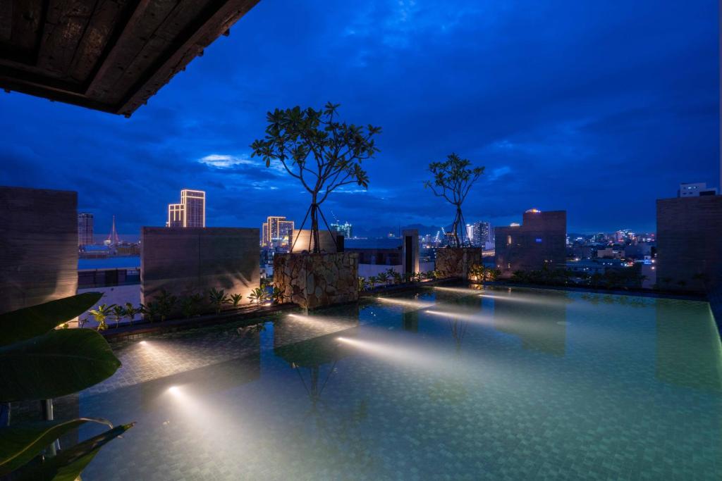 a rooftop pool with a city skyline at night at Hôtel de Soie in Danang