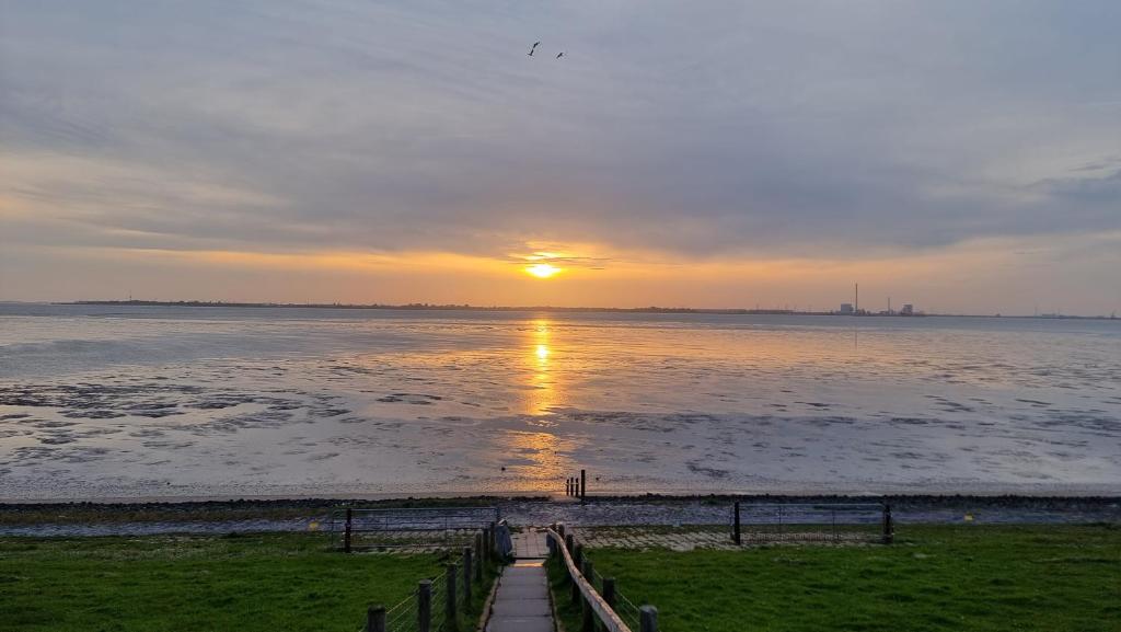 a sunset over the water with the sun setting at Ferienhaus Namenlos in Butjadingen