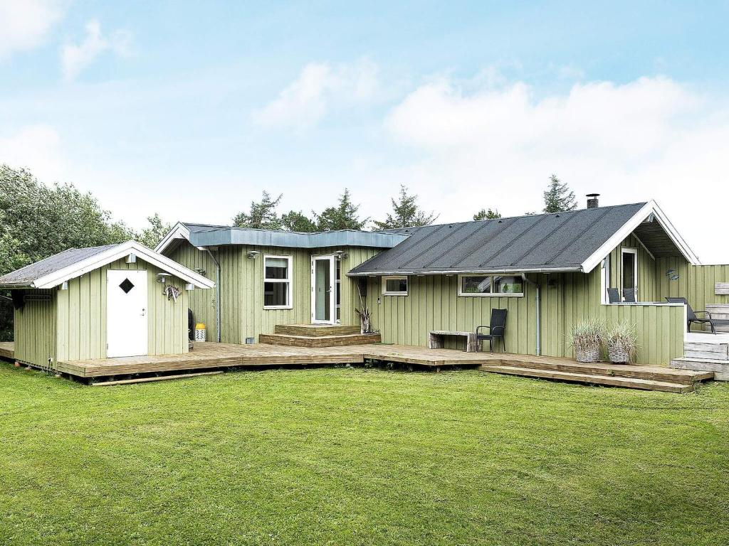 a green house with a large yard in front of it at 4 star holiday home in Jerup in Jerup