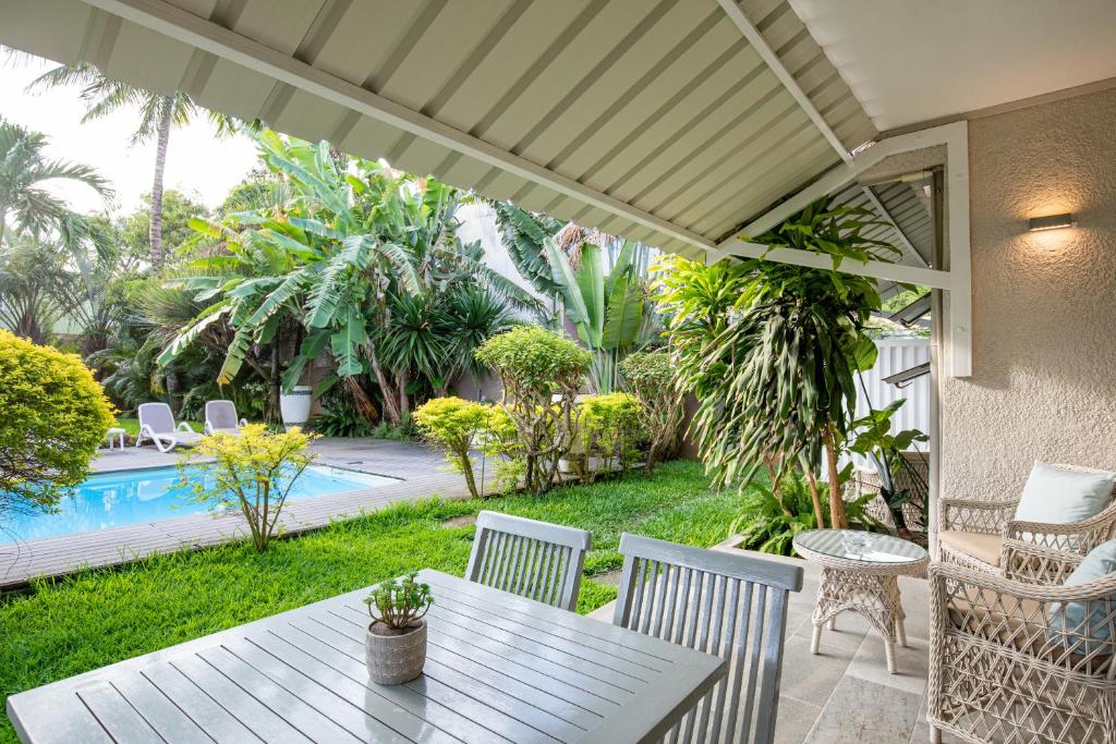 Un patio con mesa y sillas y una piscina. en Kisana Residence - Pleasant apartment with pool, close to beach, en Pointe aux Cannoniers