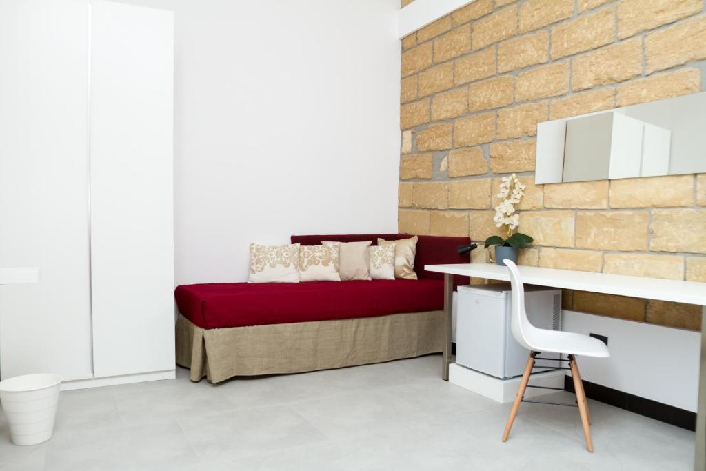 1 dormitorio con cama roja y pared de ladrillo en ARENARIA B&B, en Avola