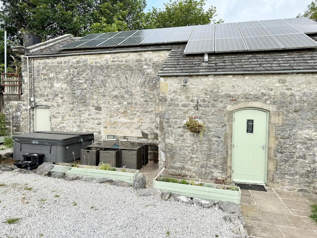 an old stone building with solar panels on it at Kilnsey Wellbeing Barn With Hot Tub, Cold Plunge, Pet Friendly in Kilnsey