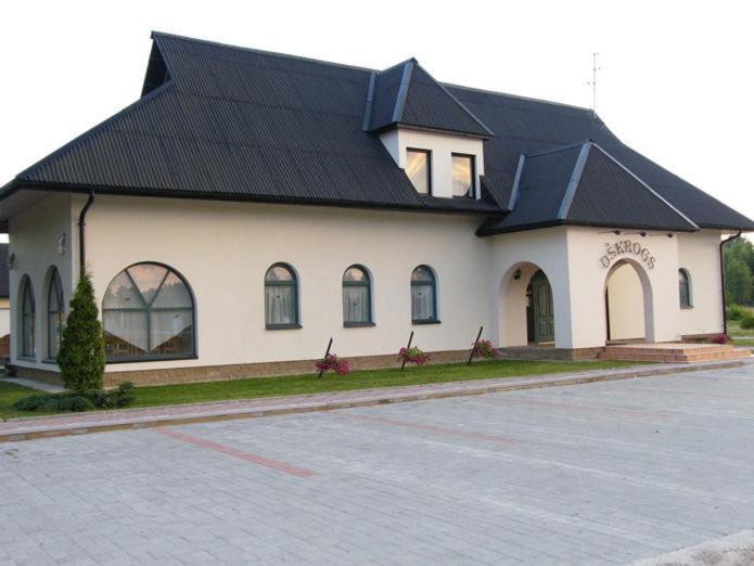 a large white building with a black roof at Oškrogs in Ķegums