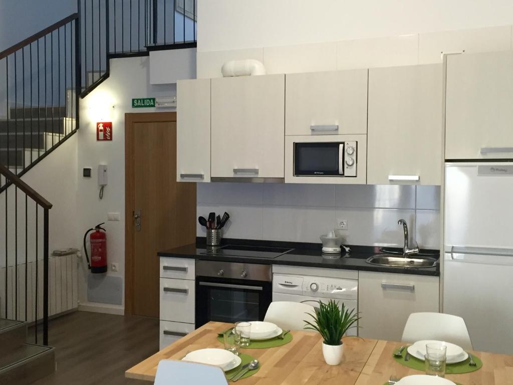 a kitchen with white cabinets and a table with chairs at Apartamentos Jurramendi - Los Arcos in Los Arcos