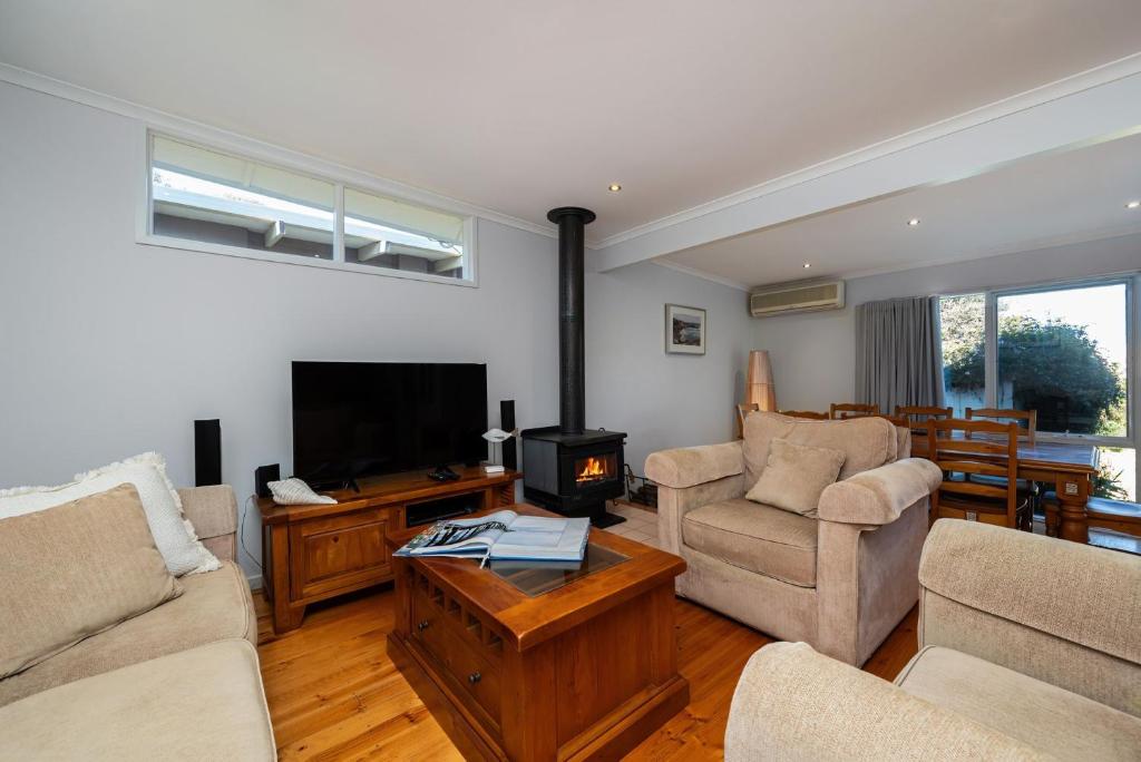 a living room with couches and a tv and a fireplace at Hilltop Cottage - Beachside Escape with Fireplace in Blairgowrie