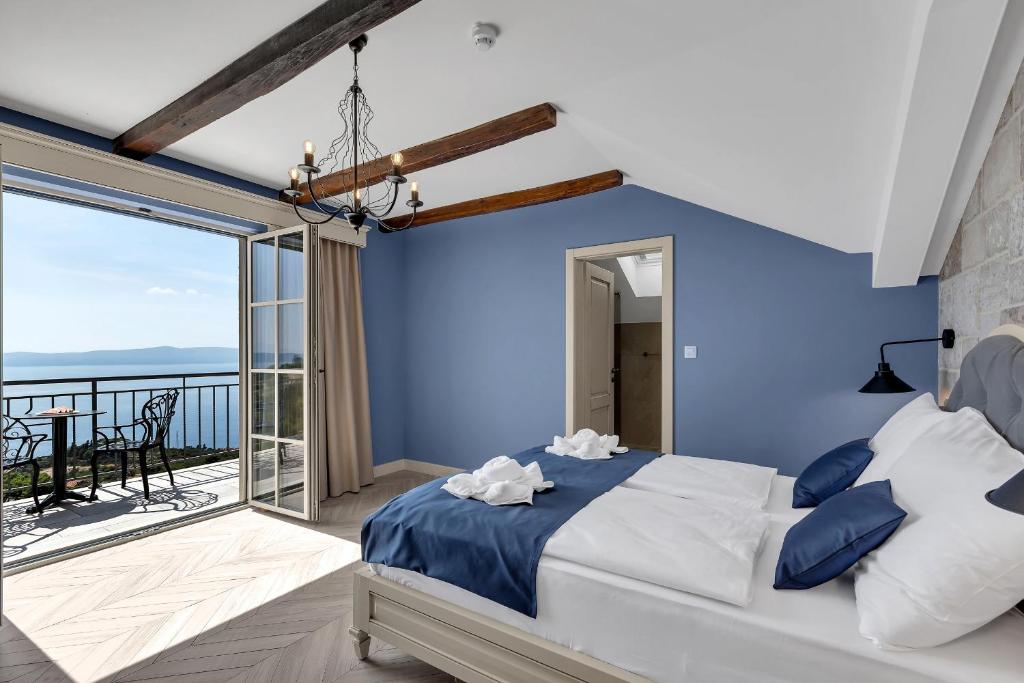 a blue bedroom with a bed and a balcony at Hotel Liberan - Nature's Retreat in Podgora