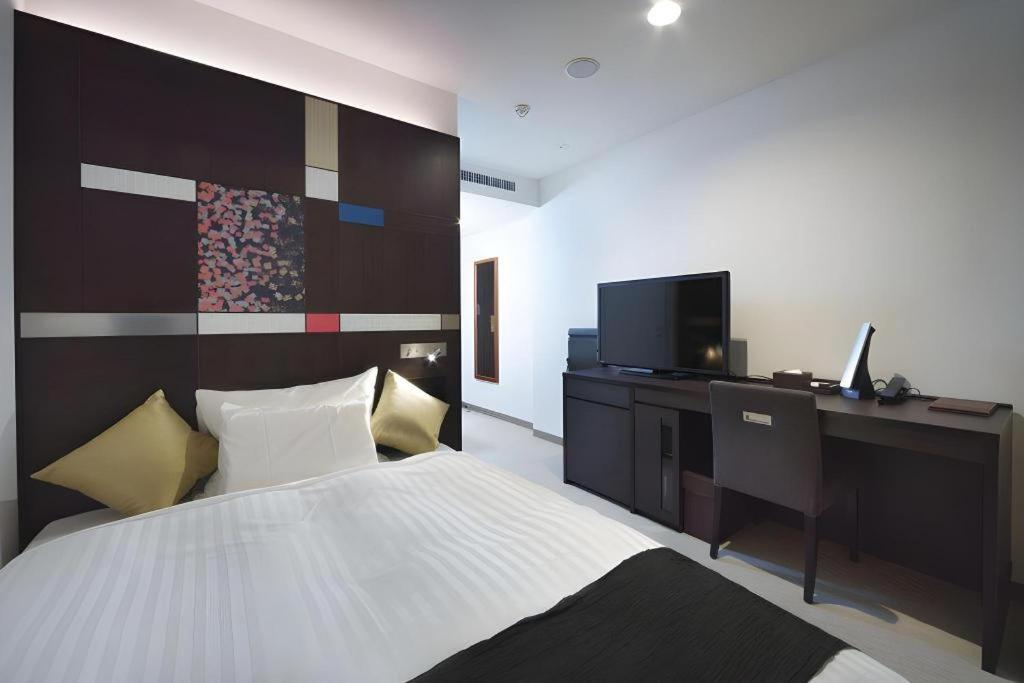 a bedroom with a bed and a desk and a television at JR-EAST HOTEL METS NAGAOKA in Nagaoka