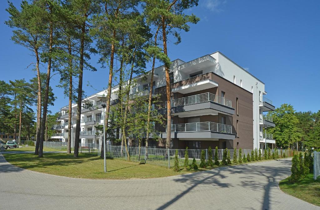 ein Mehrfamilienhaus mit Bäumen davor in der Unterkunft Komfortowe Apartamenty Sun Seasons 24 w Pogorzelicy Blisko Morza by Noclegi Renters in Pogorzelica