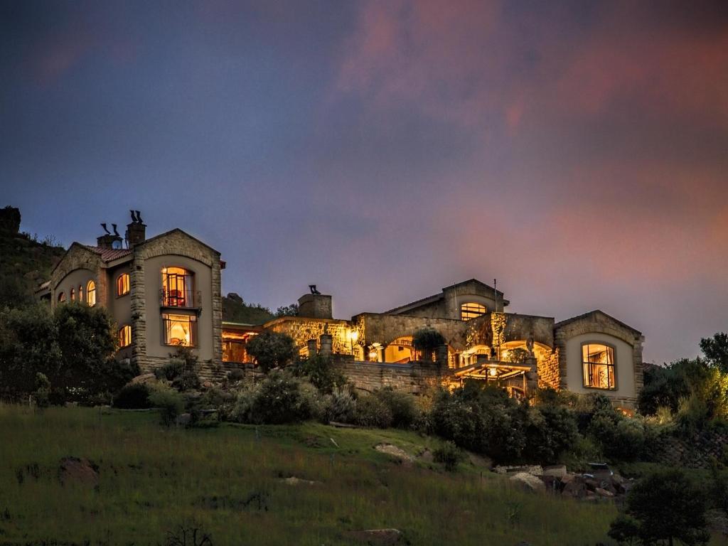 a large stone house with lights on at Wild Horses Lodge in Harrismith