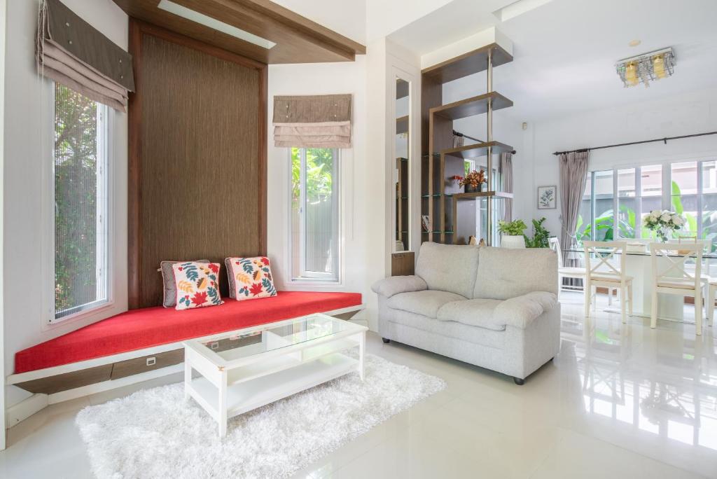 a living room with a red couch and a chair at Elegant and Modern Home at Sansaran Villa Chiang Mai in Ban Phae Khwang